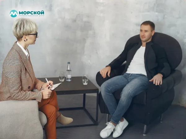 Мужчина сидит на приеме у психолога в кабинете