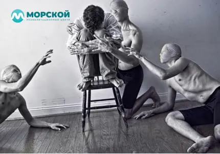 Испуганный мужчина на стуле и три фигуры рядом